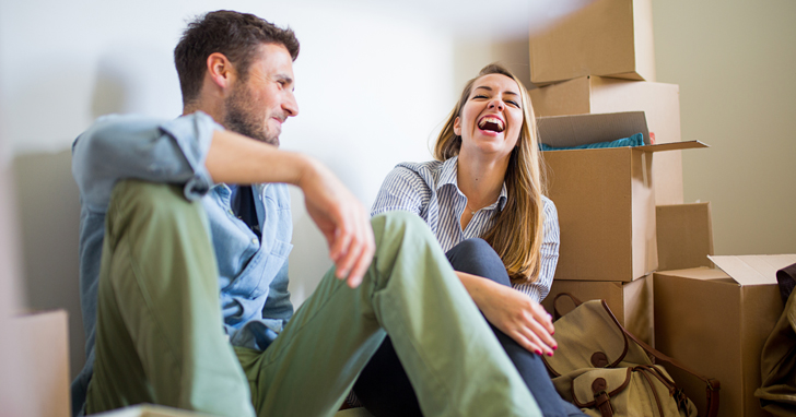 Young couple laughing with moving boxes in background