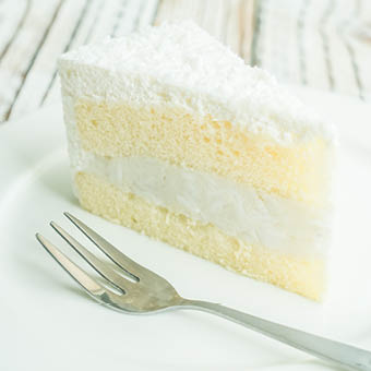 two layered white coconut cake slice on a plate